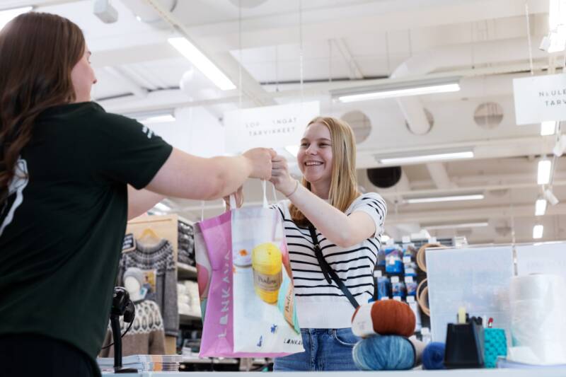 Myymälän kassalla asiakas tyytyväisenä.
