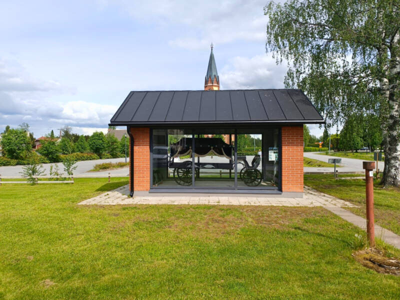 Ruumisvaunut vitriinissä, takana Kauhavan kirkko.