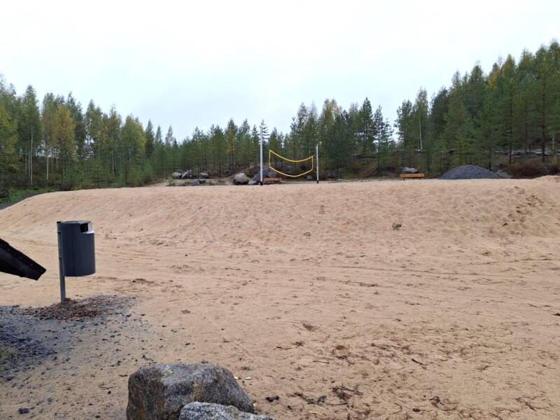 Hiekkarantaa ja lentopalloverkko.